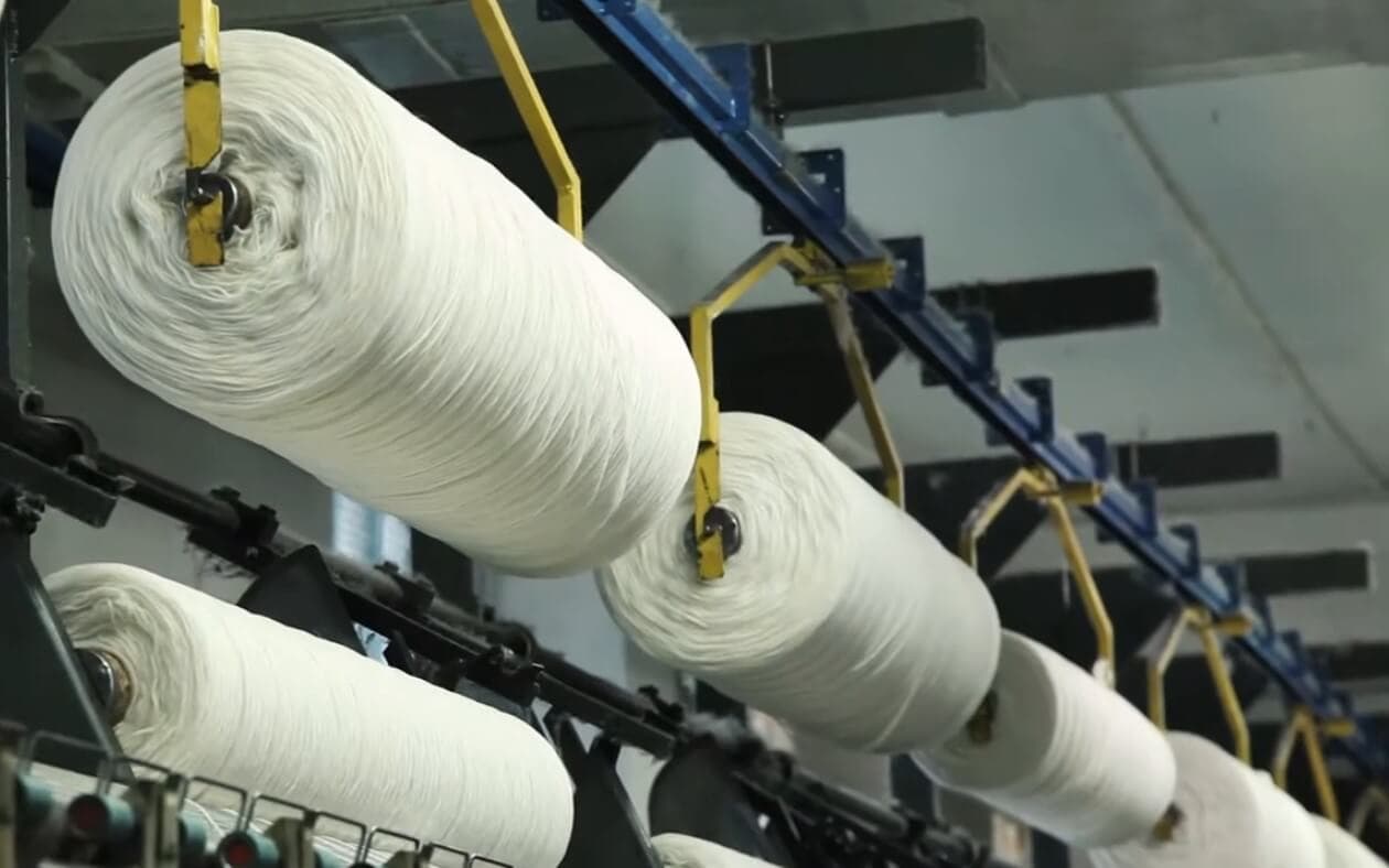 Close-up of a weaving machine aligning dark and light wool threads