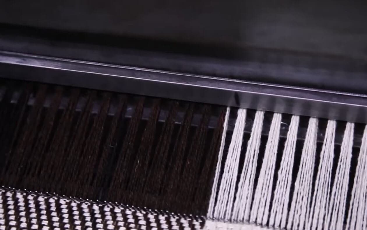 Large spools of white natural yarn on a spinning machine
